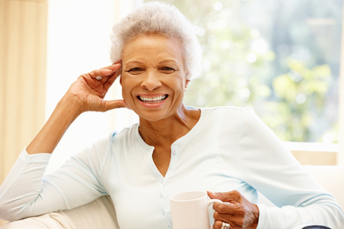 Smiling african american woman sitting on a couch holding a coffee cup